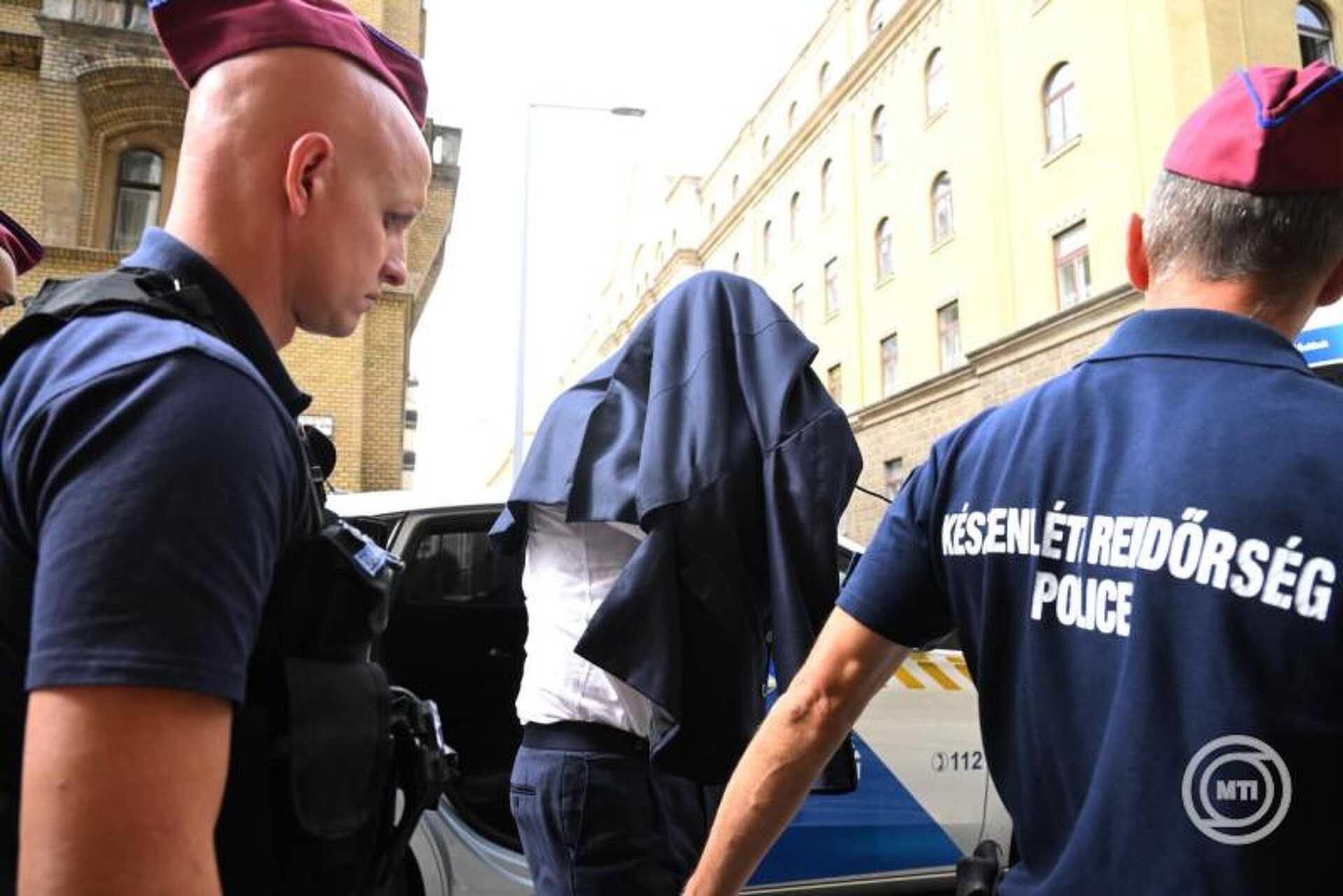 Rendőrök vezetnek egy gyanúsítottat a Fővárosi Büntetés-végrehajtási Intézetbe 